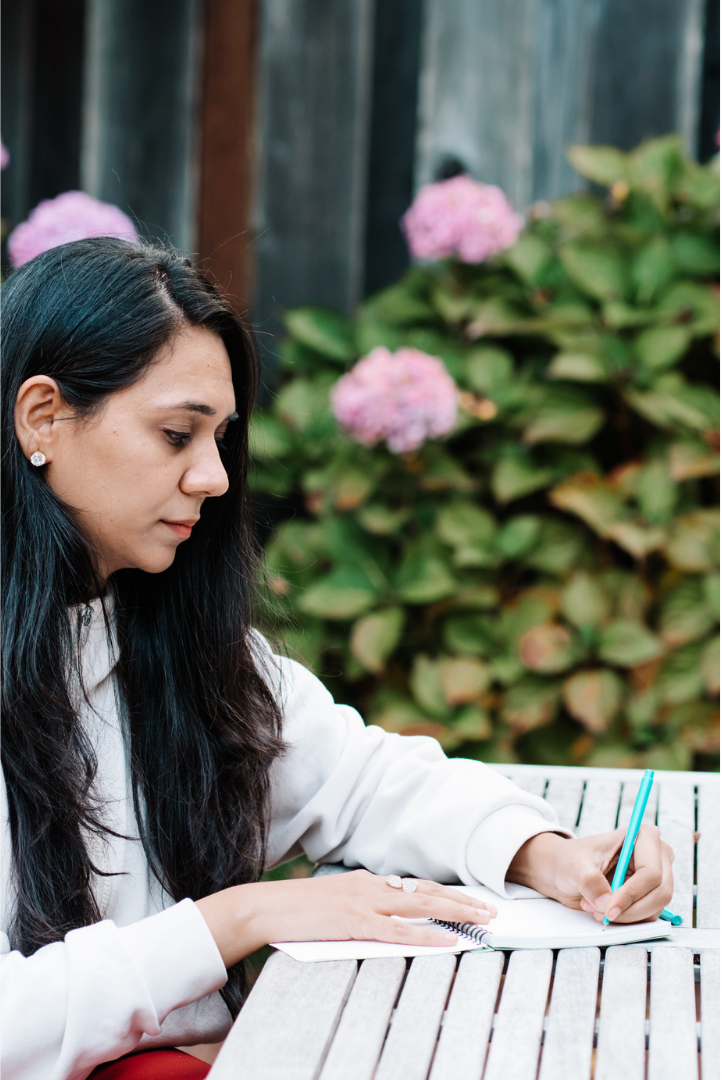 Woman journaling outdoors creating her personalized Ayurvedic daily wellness routine